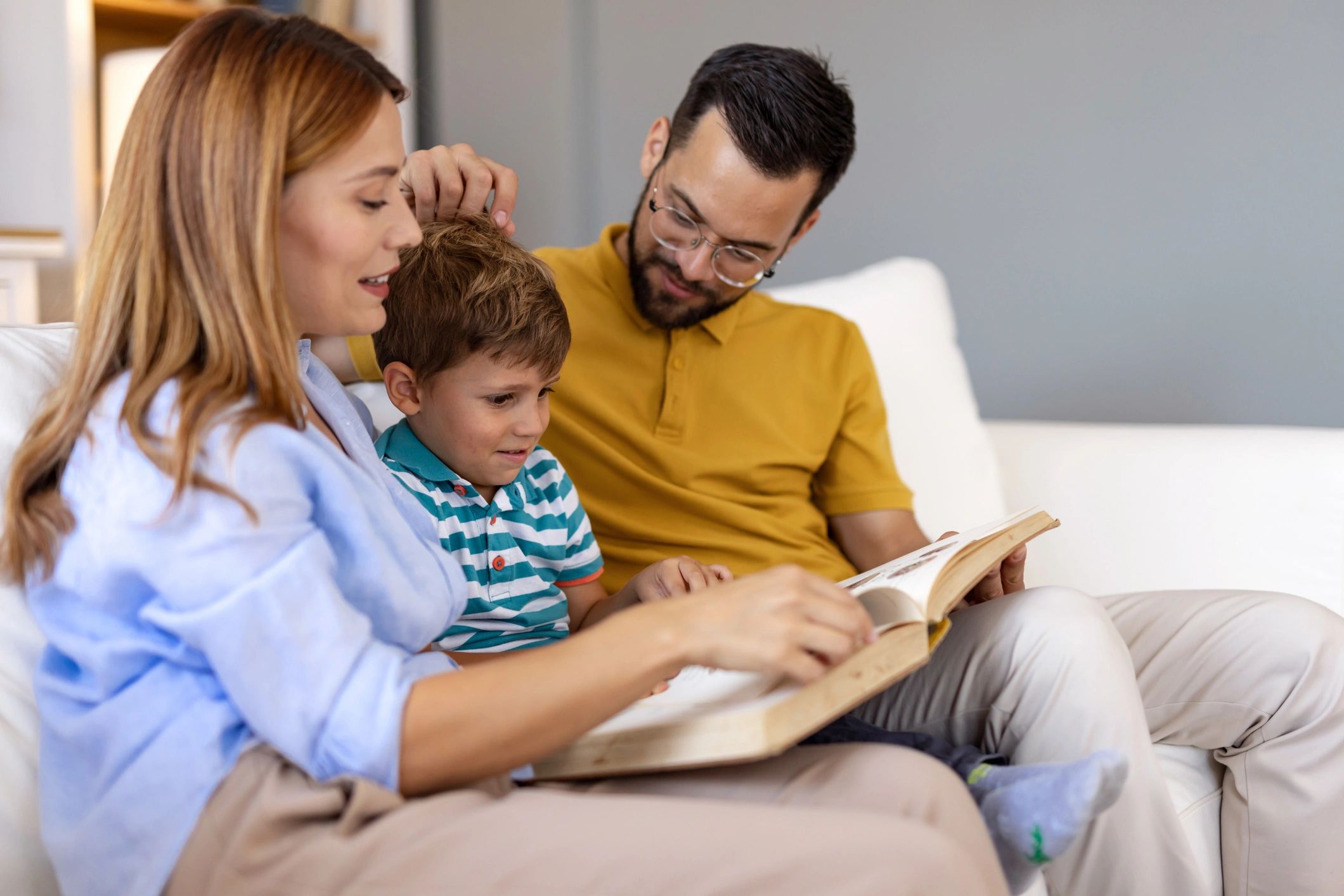 Parents and child reading together on a couch